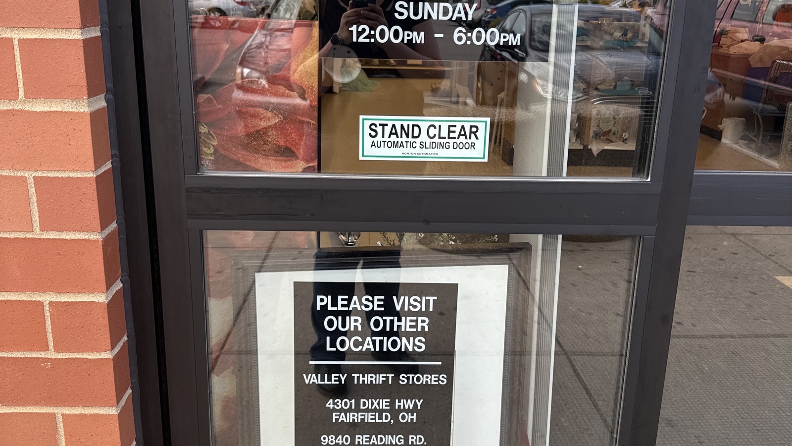 Entrance door with store hours and Valley Thrift Store location information