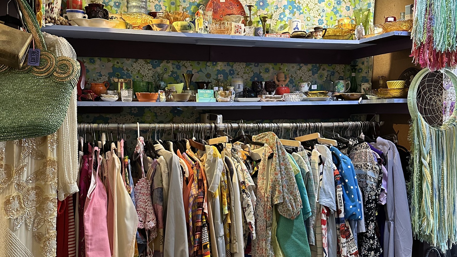 Colorful vintage clothing hanging beneath art and handmade displays at Design Archives in Winston-Salem