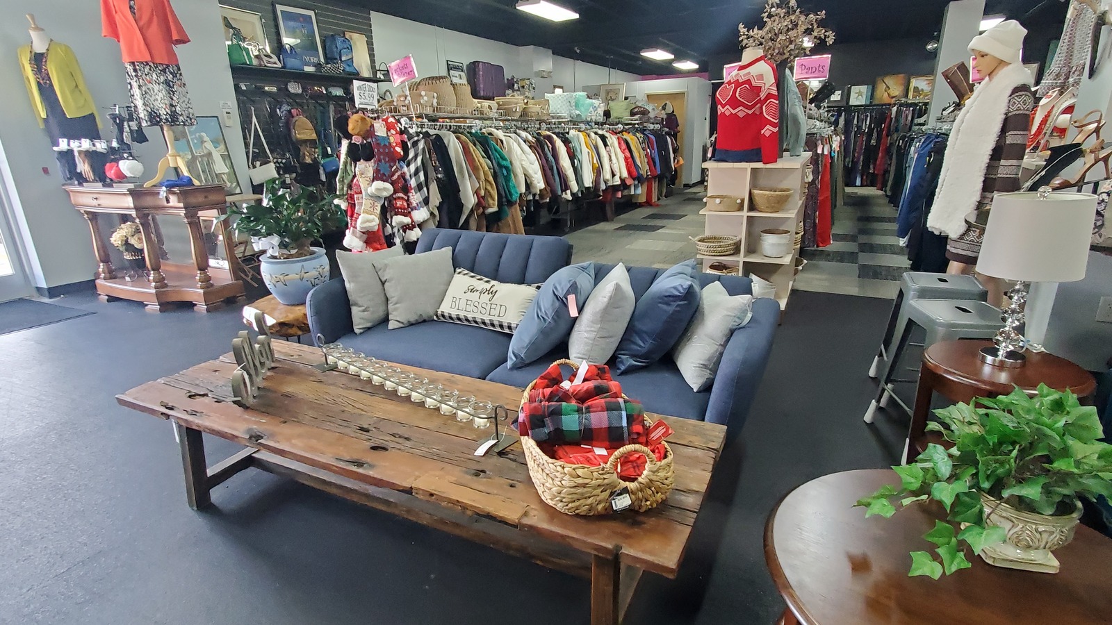 A sofa, coffee table, clothing racks, and seasonal decor inside Out Of The Box Consignment in Winston-Salem