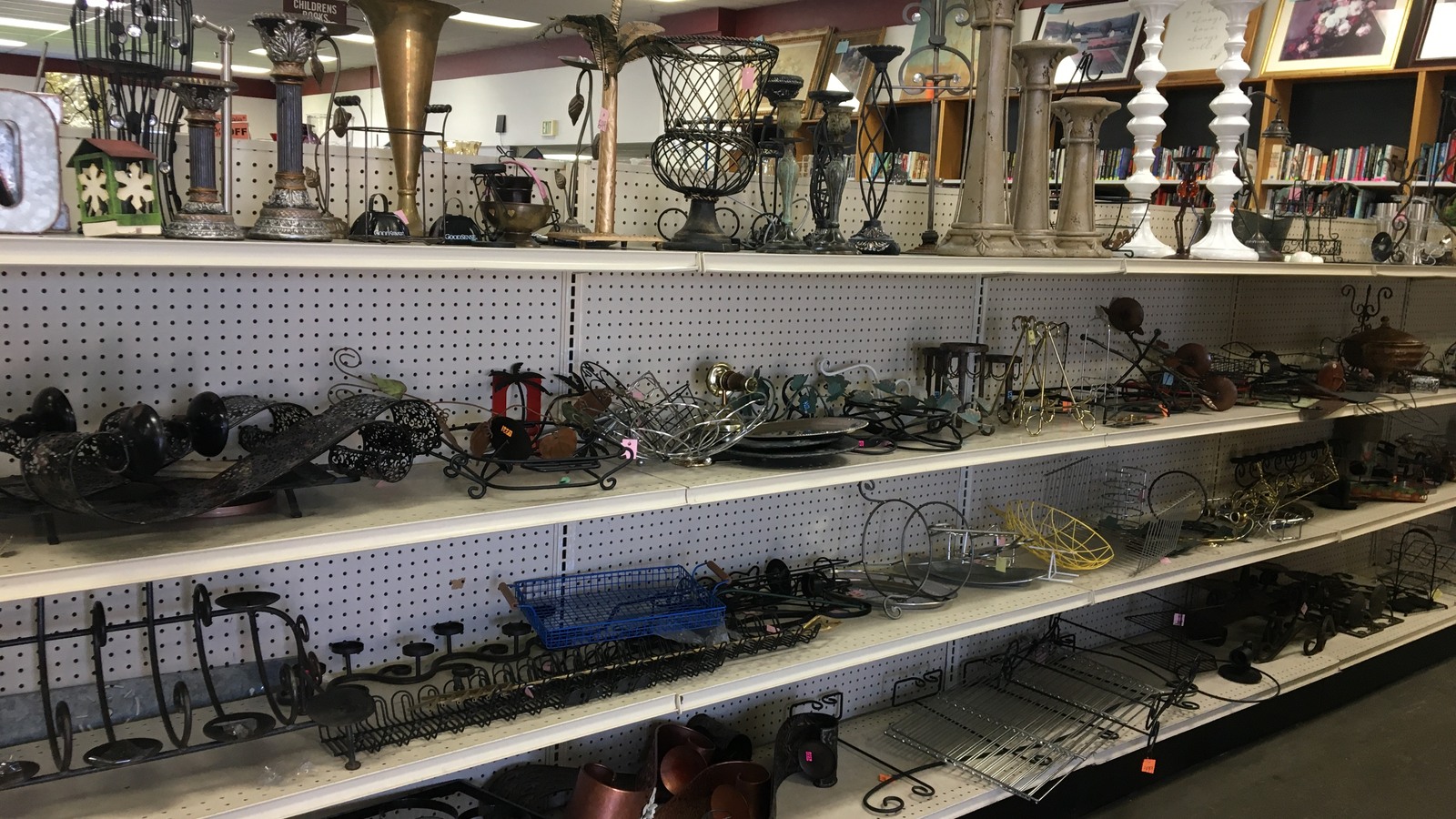 Metal candleholders and decorative accents on pegboard shelves