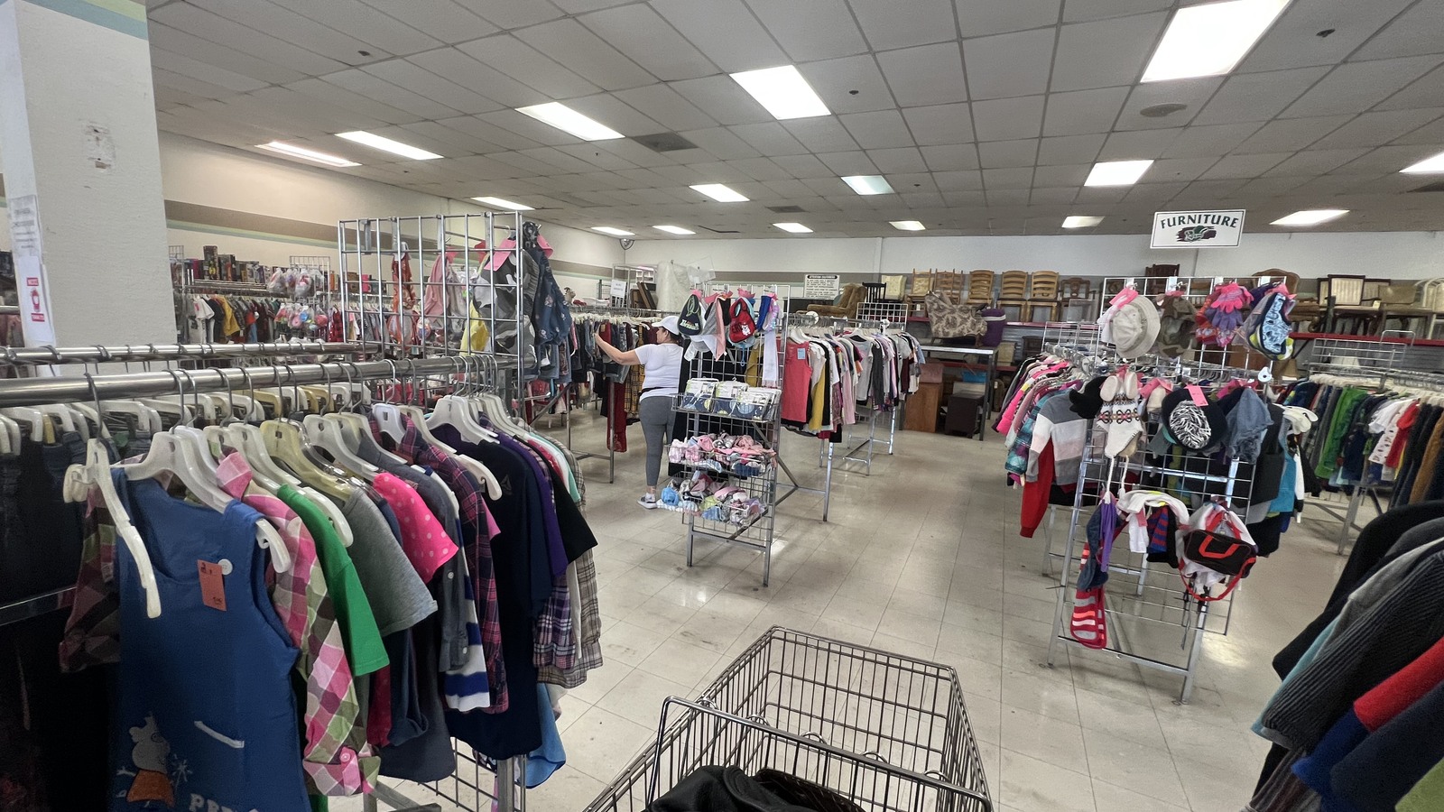 Long clothing racks across the bright sales floor at Quality Thrift Store