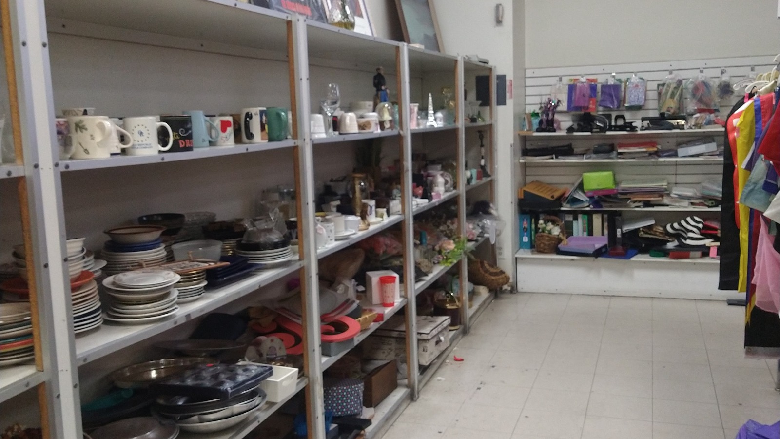 Shelves of dishes, mugs, cookware, and secondhand housewares