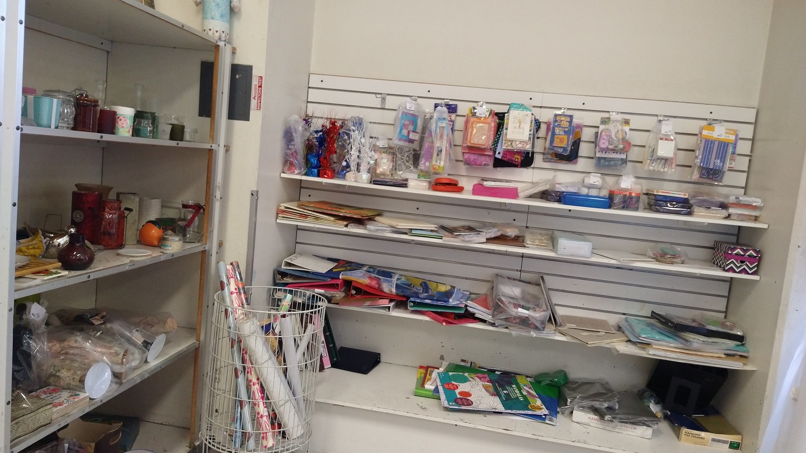 Ribbons, paper goods, and craft supplies arranged on white shelves