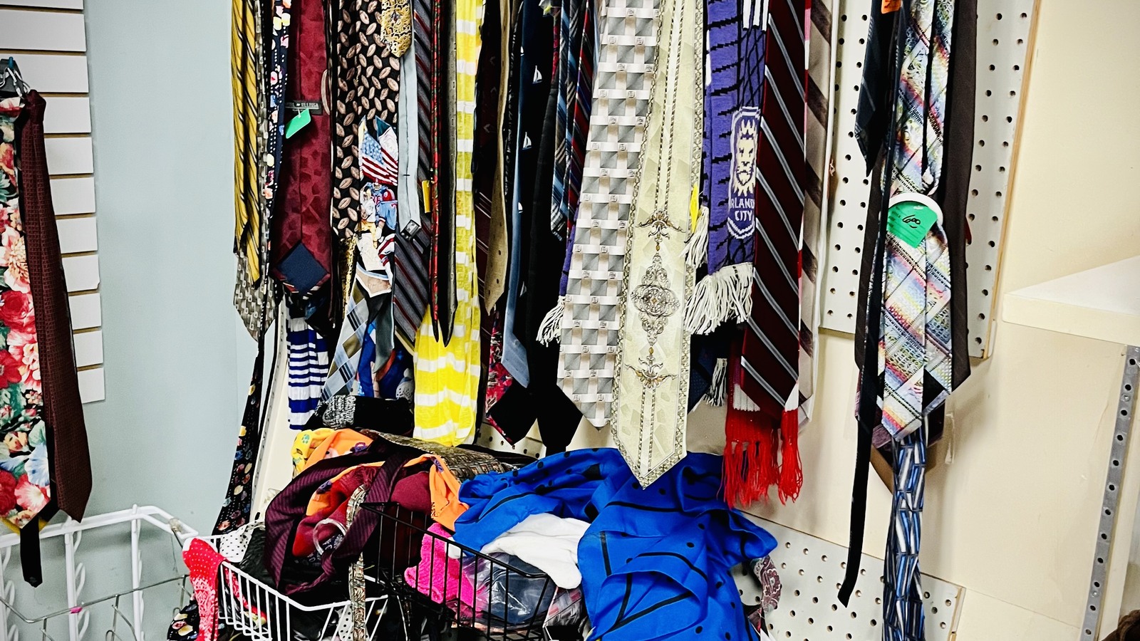 Colorful ties, scarves, and accessories hanging on a wall display