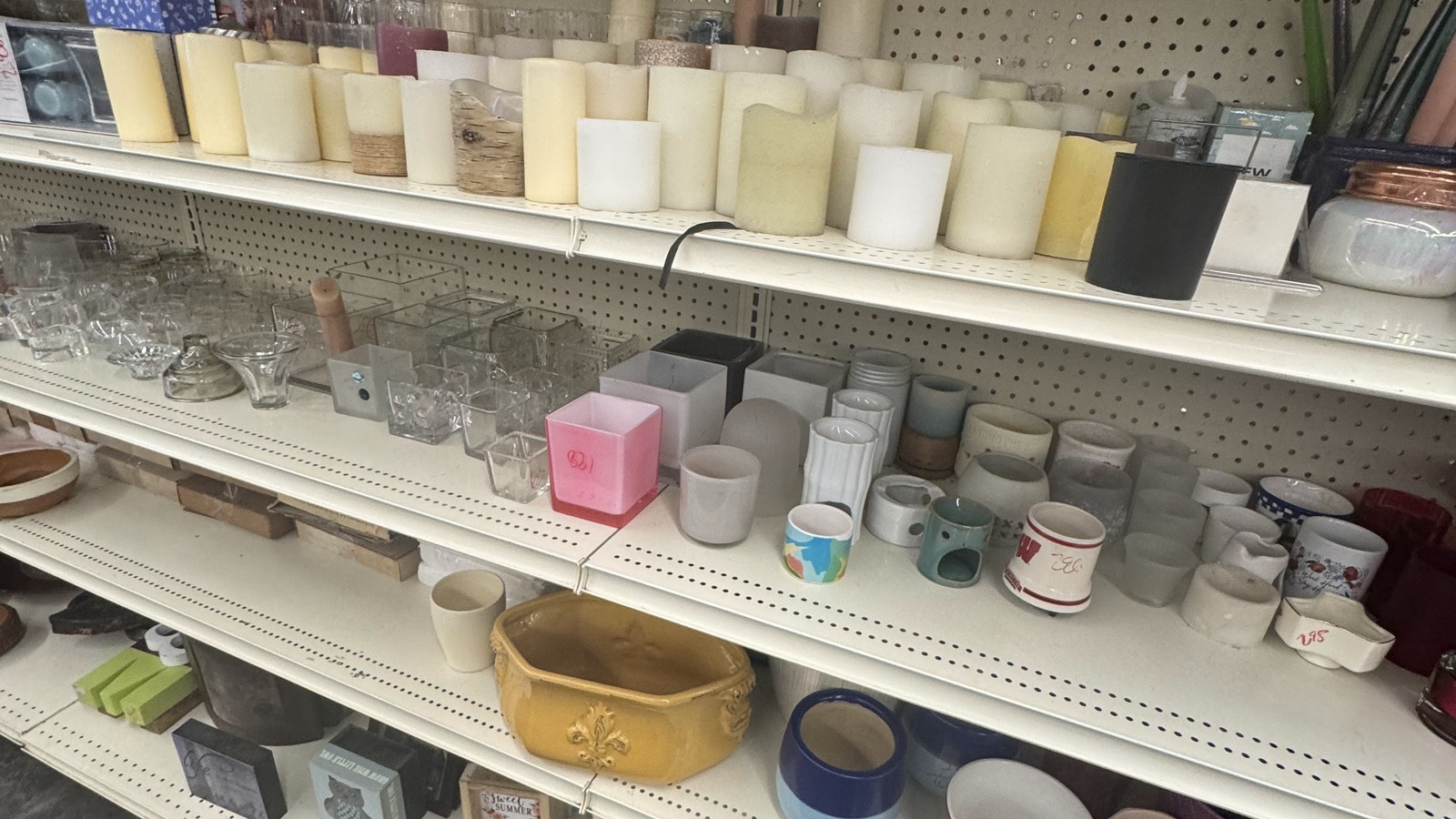 Candles, mugs, and small home accents on white shelves