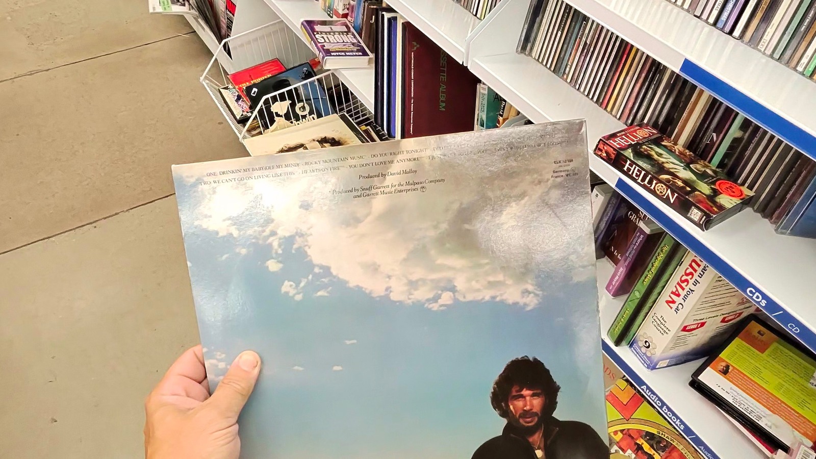 Vinyl album held beside music shelves at Savers in Scottsdale