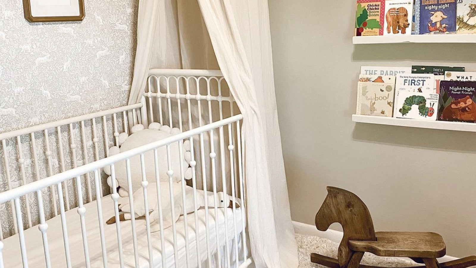 White crib, rocking horse, and children's books in a decorated room