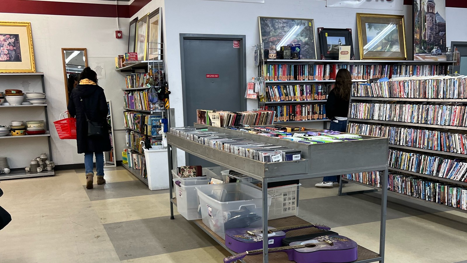 Shelves of books and media beside a browsing table