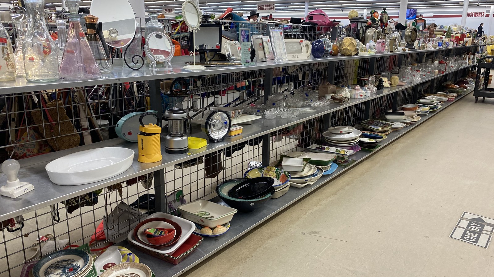Long housewares aisle filled with dishes, clocks, and kitchen pieces