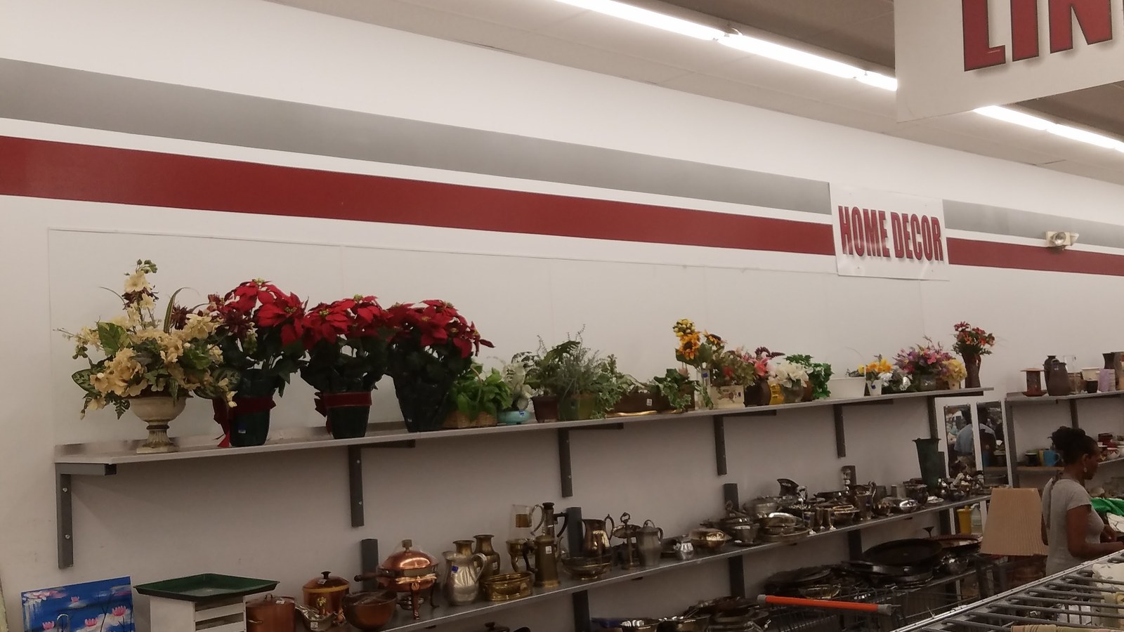Artificial floral arrangements and home accents along a wall shelf