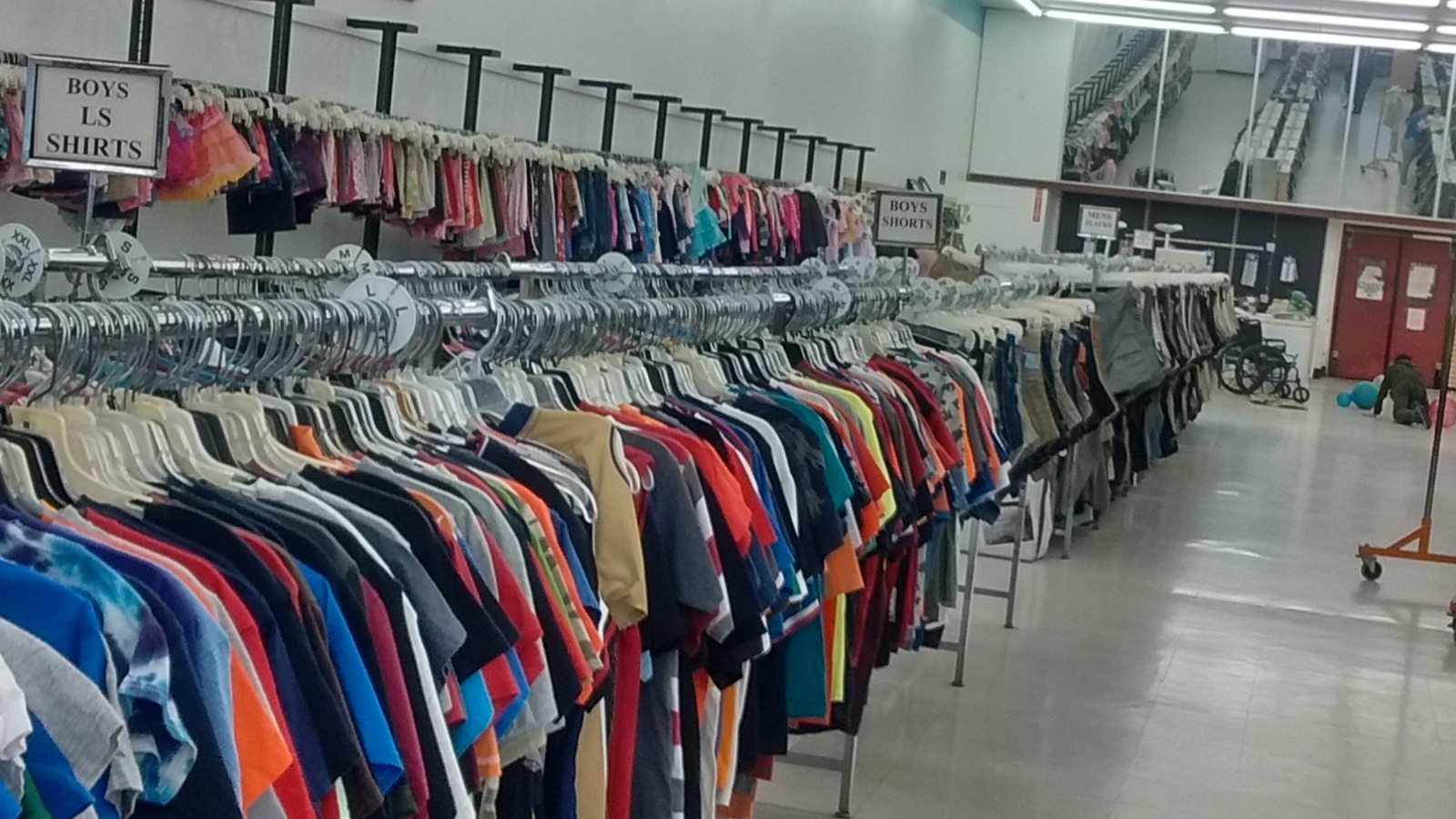 Long organized racks of colorful shirts and jackets inside Carolina Value Thrift in Gastonia