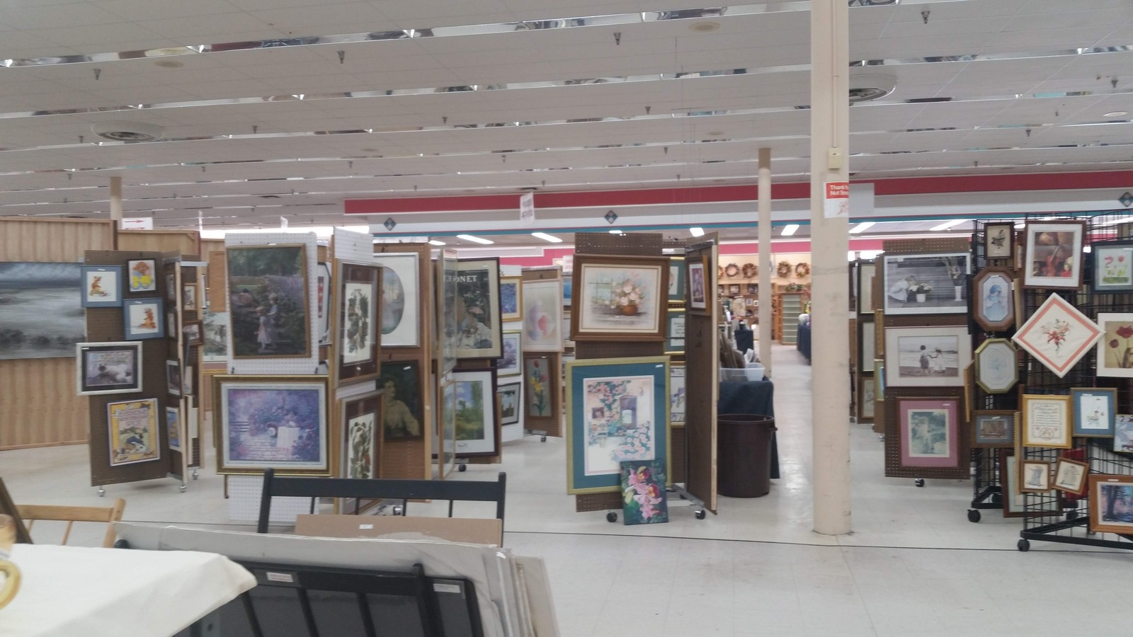 Framed artwork displayed on freestanding panels at the thrift store