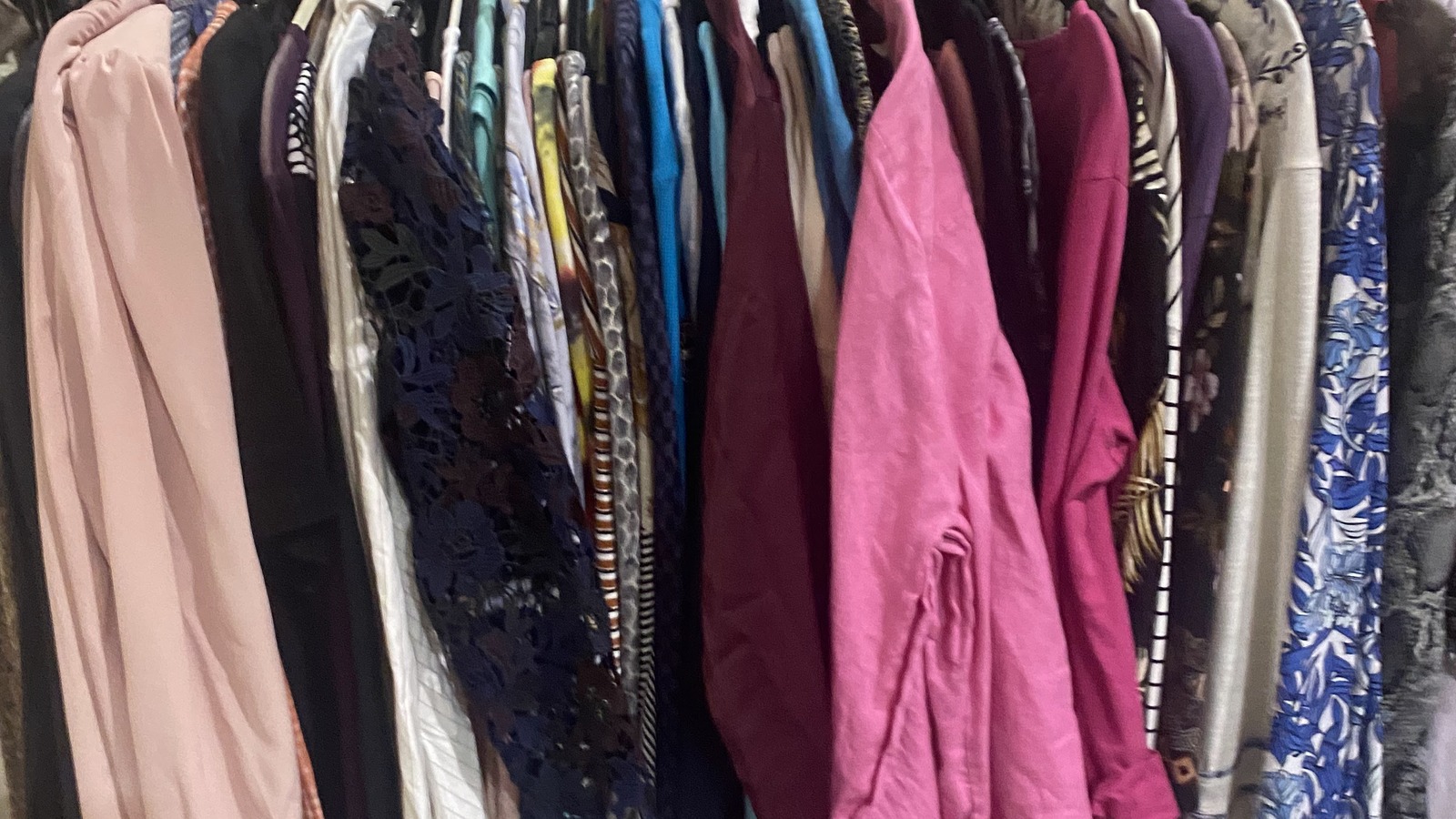 Colorful secondhand clothing arranged on racks at Brown Elephant