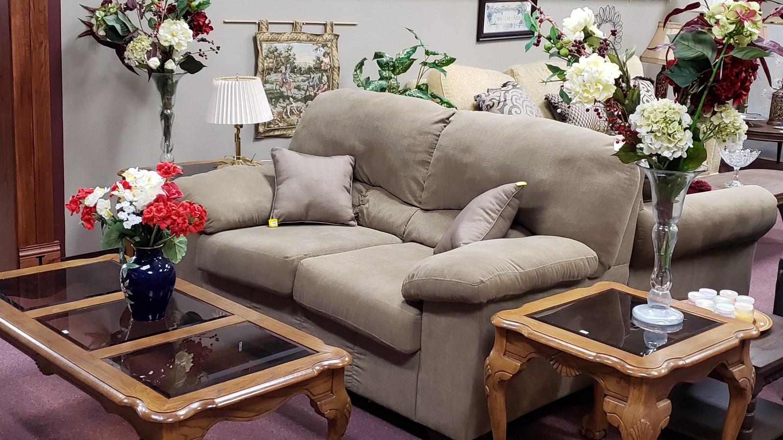 Sofa, wood tables, lamps, and floral arrangements in the furniture department