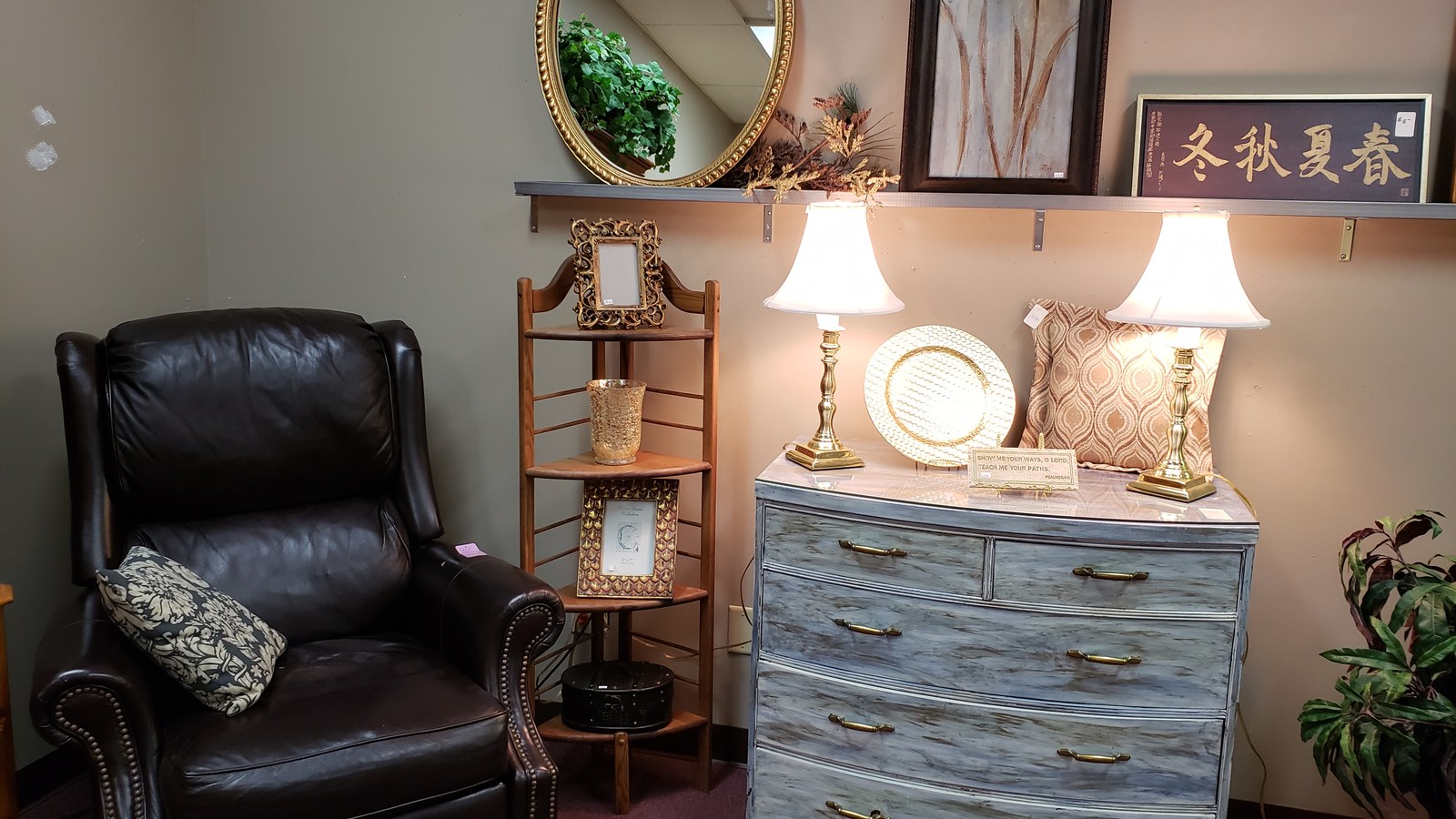 Table lamps, a round mirror, and a painted accent cabinet on display