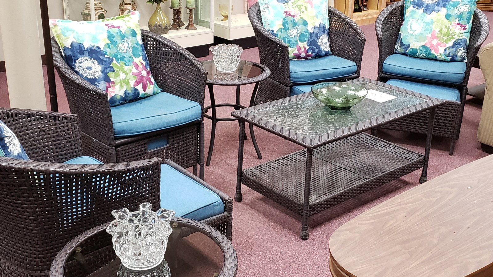 Woven patio chairs with blue floral cushions and a matching table