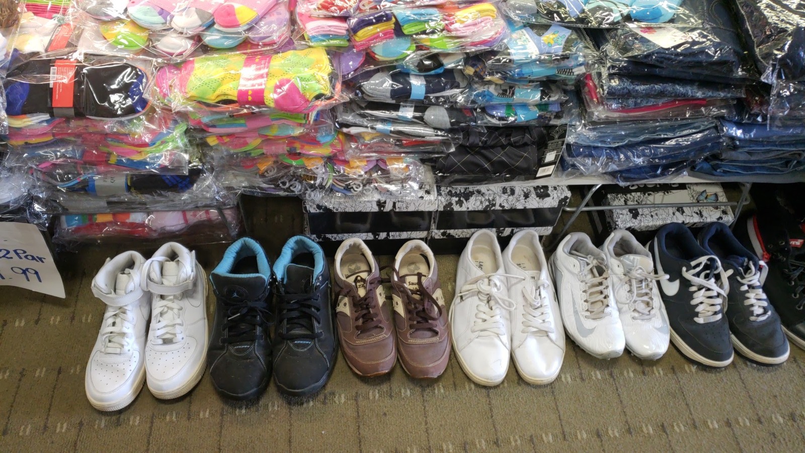 Sneakers beneath stacks of colorful folded clothing