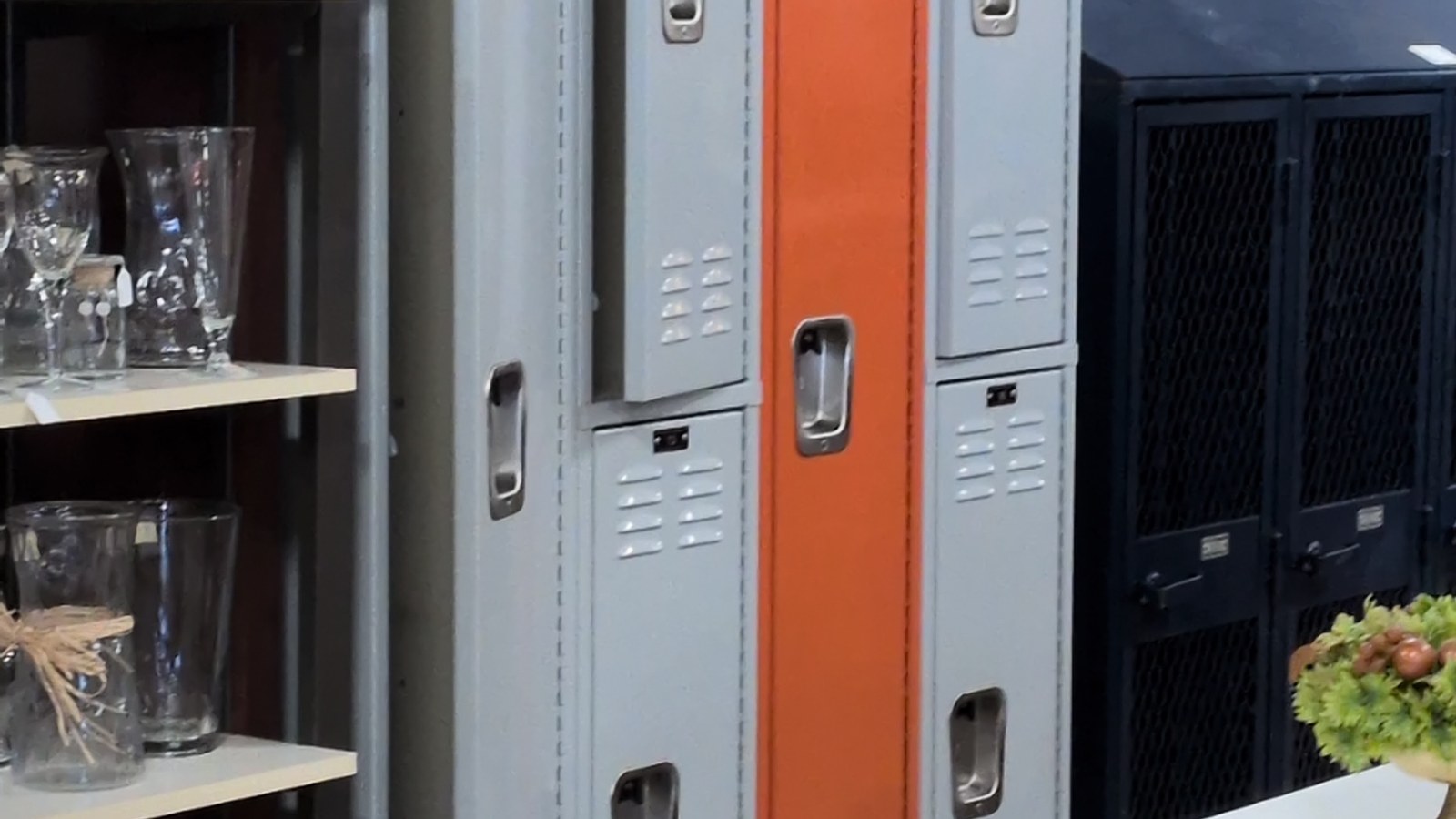 Gray, orange, and black metal lockers beside glassware shelves