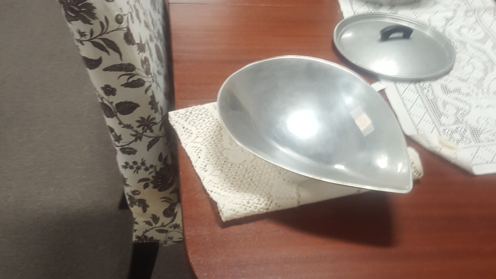 Silver metal pendant light resting on a wood table