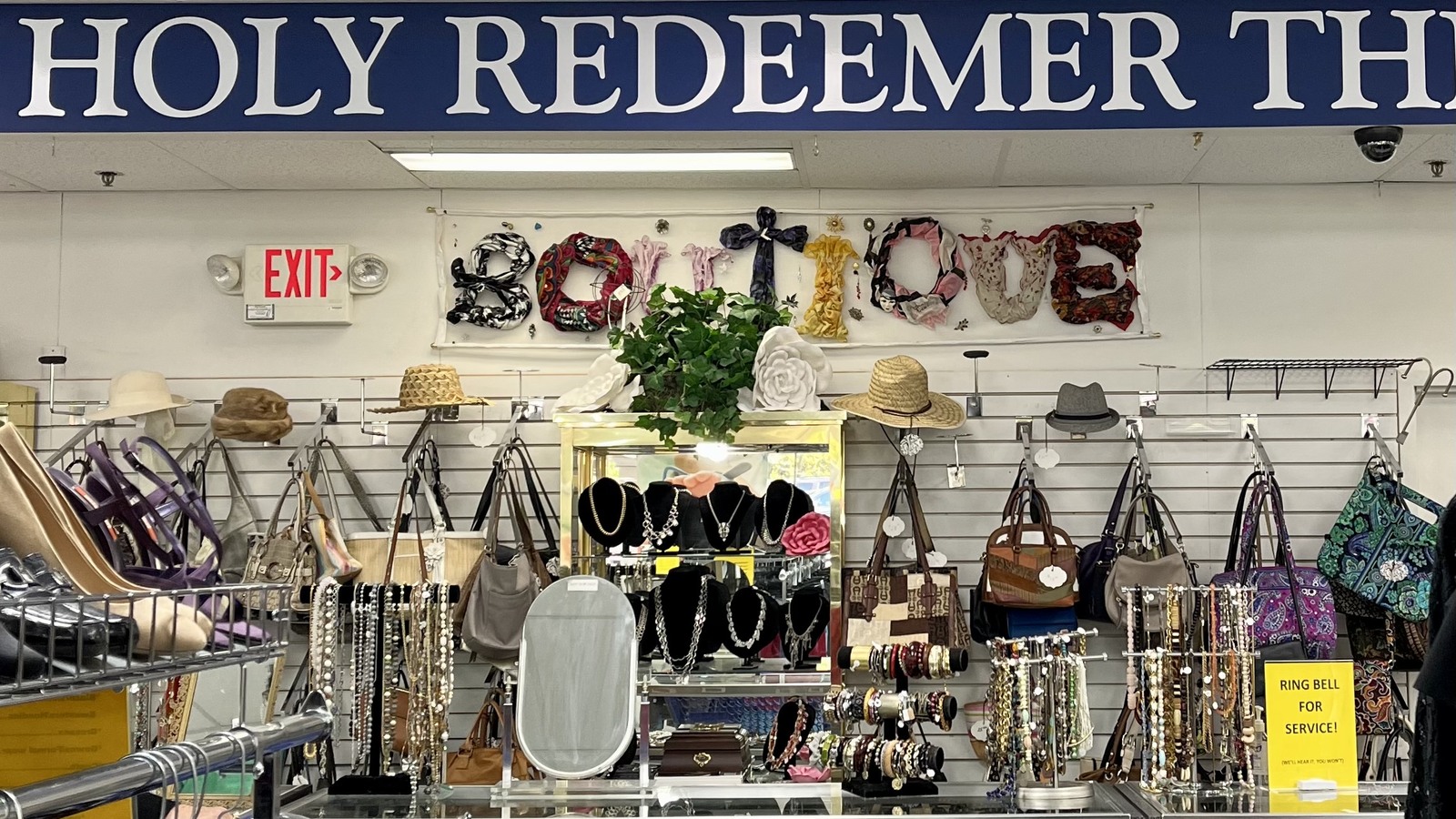 Handbags, hats, necklaces, and accessories arranged by the Holy Redeemer sign