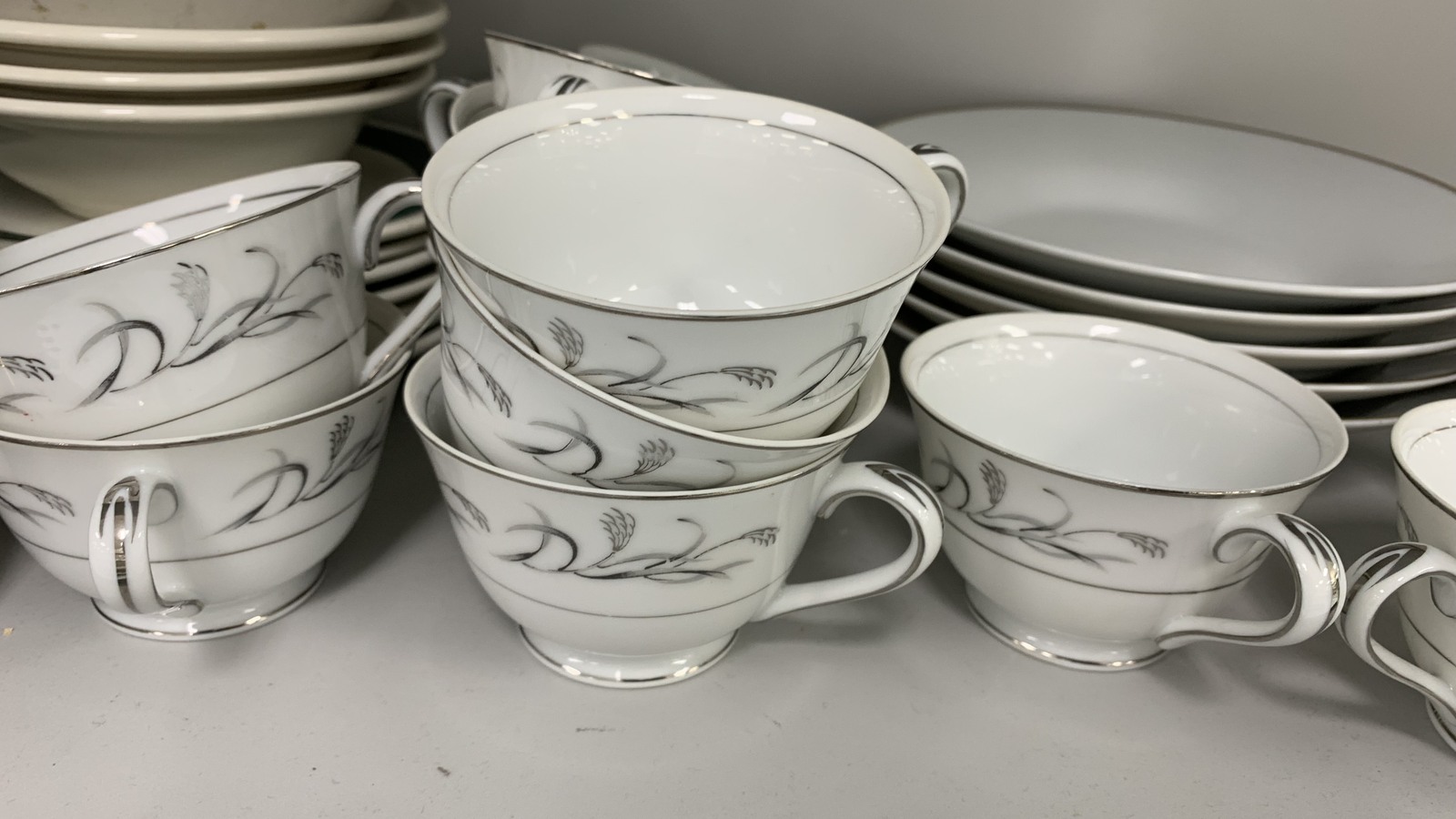 Coordinated dishes, teacups, and serving pieces on white shelves