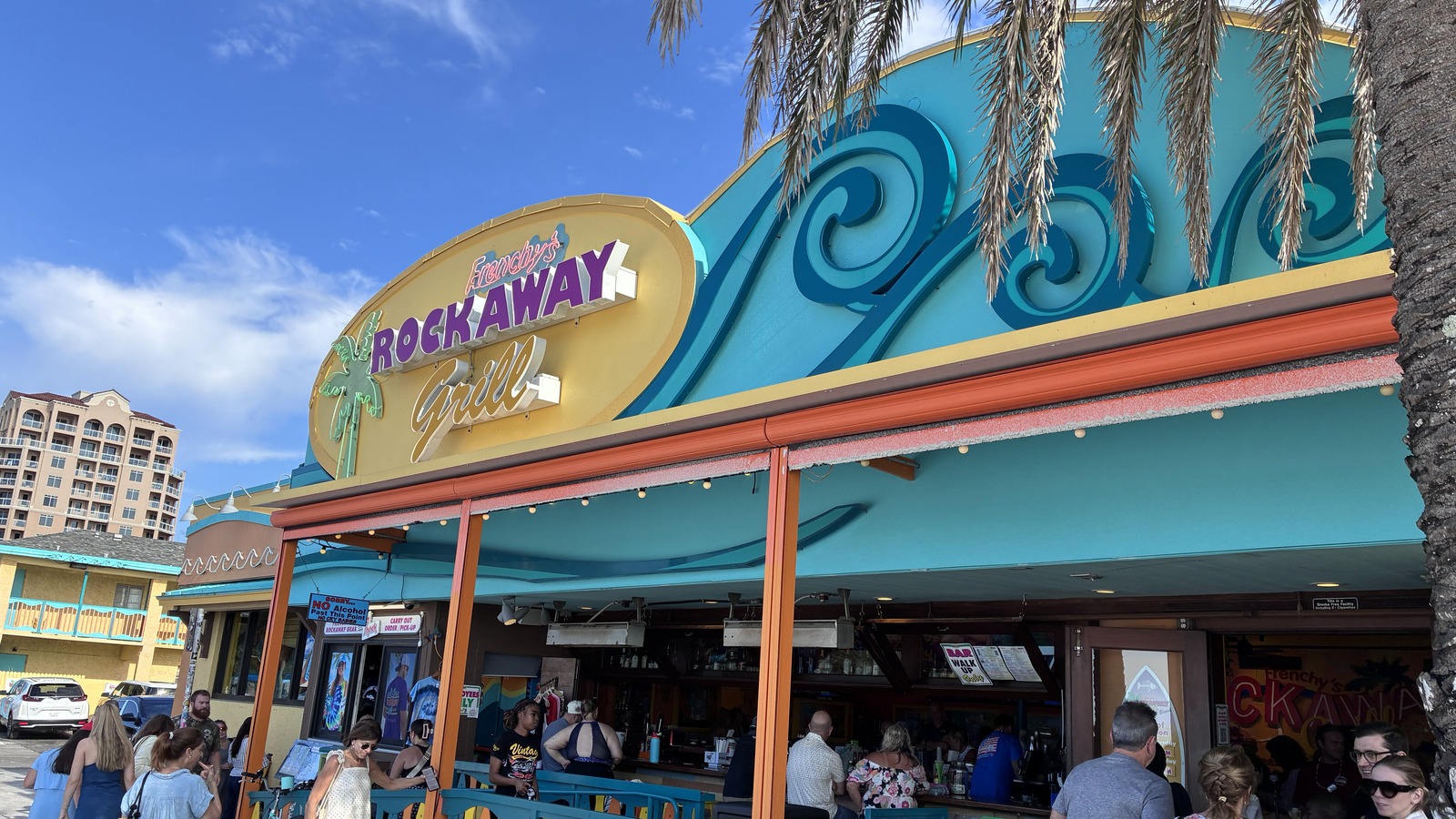 Frenchy's Rockaway Grill facade with turquoise waves and palm fronds in daylight