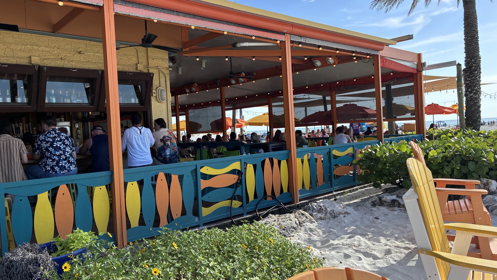 Open-air side patio and colorful rail beside the sand at Frenchy's Rockaway Grill