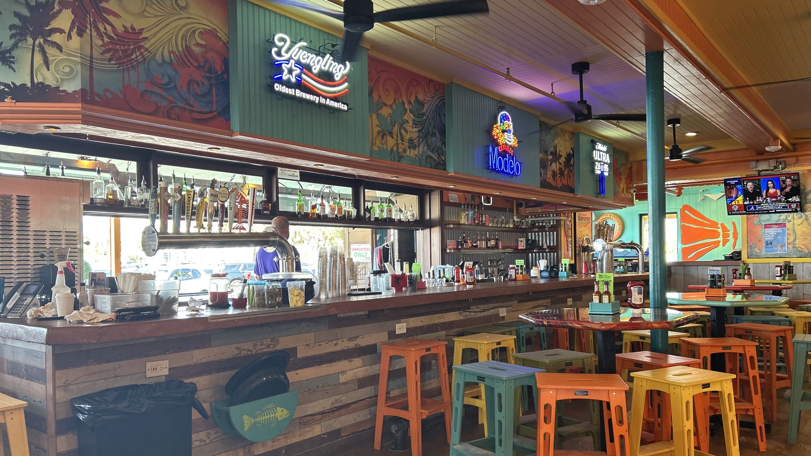 Colorful indoor bar with neon signs and bright stools at Frenchy's Rockaway Grill
