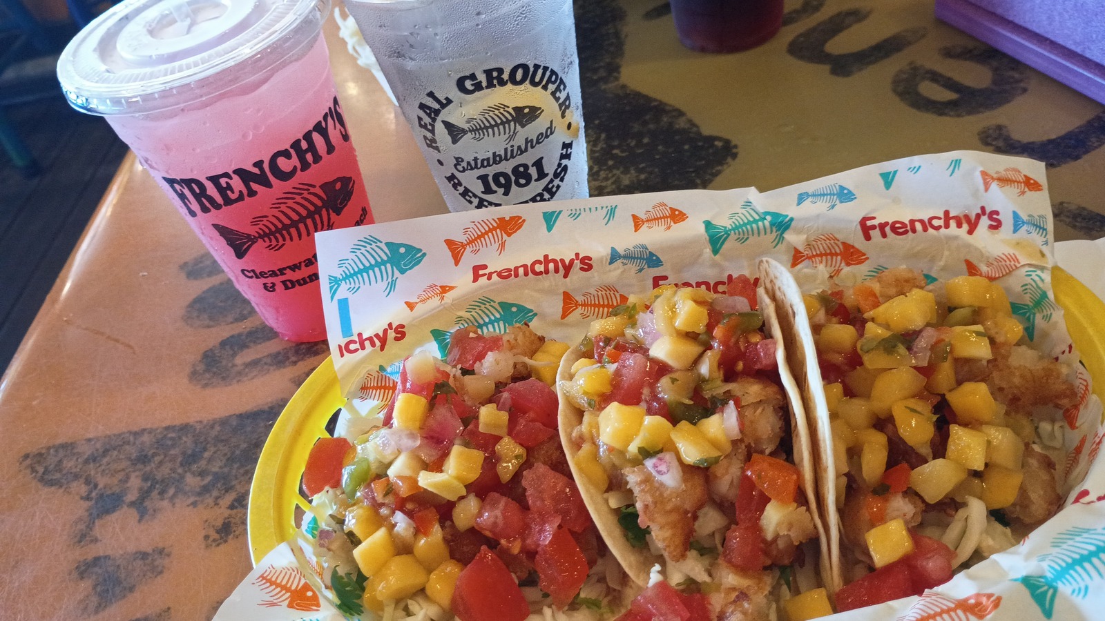 Fish tacos and bright frozen drinks on a branded Frenchy's table