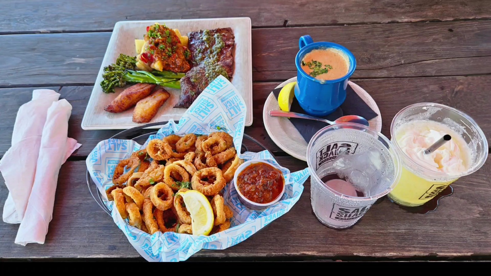 Table spread with calamari, seafood plates, bisque, and frozen drinks at Salt Shack On The Bay