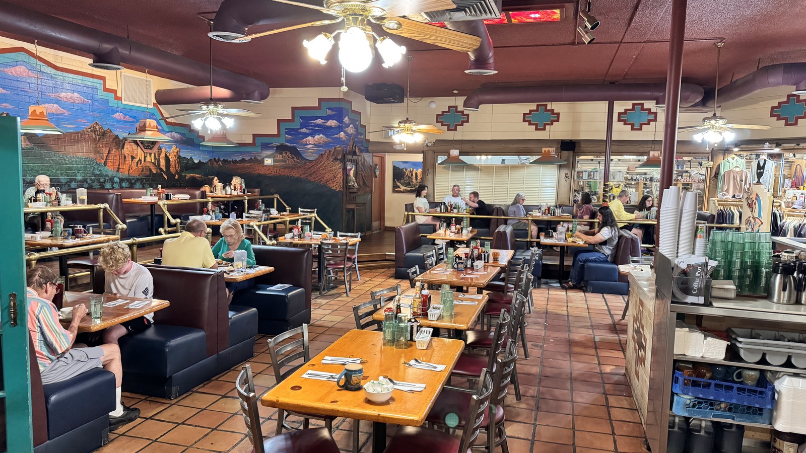 Booths, terracotta floors, and a red rock mural inside Coffee Pot Restaurant