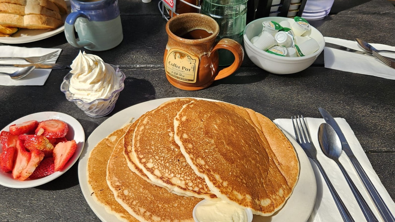 Large pancakes with strawberries and a Coffee Pot Restaurant mug