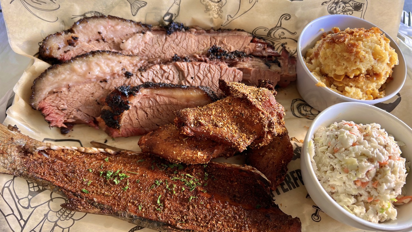 Smoked fish, sliced brisket, corn casserole, and slaw on a generous platter at Rusty Bellies