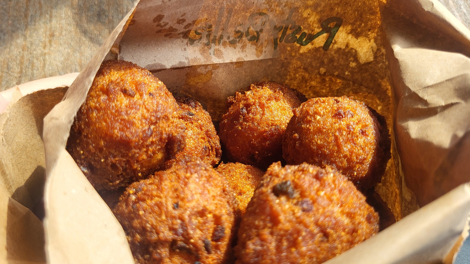 Golden hush puppies served warm in a paper-lined bag at Rusty Bellies