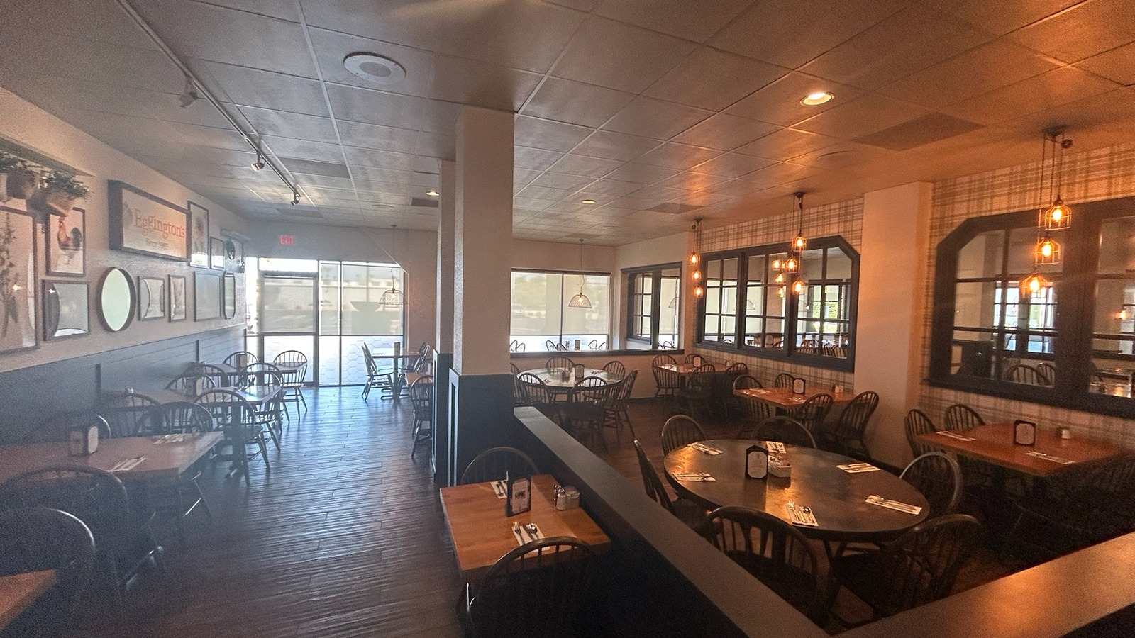 Warm dining room with plaid walls, pendant lights, and wood tables at T.C. Eggington's