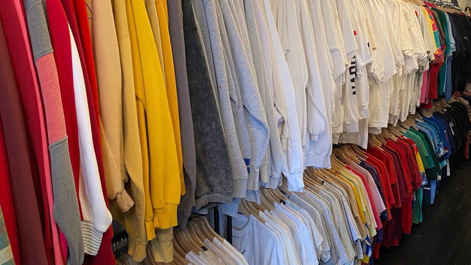 Color-sorted vintage shirts hanging in a bright rack at Fifty One Ten Vintage in Pittsburgh