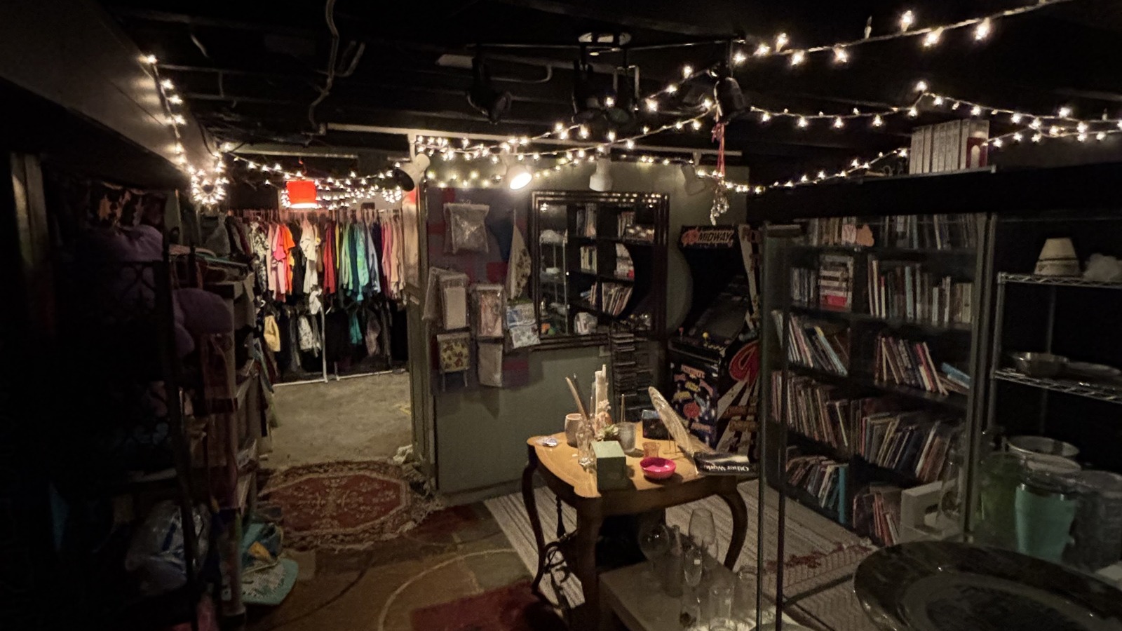Warm string lights, bookshelves, and clothing racks inside Khlovan's Thrift in Scranton