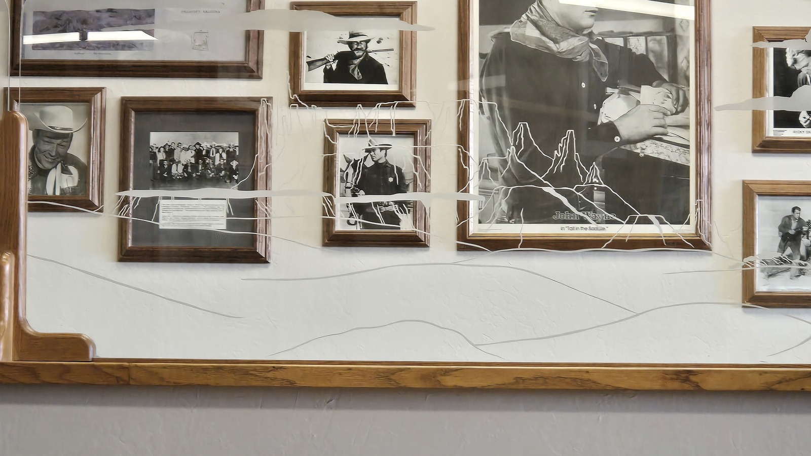 John Wayne portraits and framed western photos above a table at Zeke's Eatin' Place