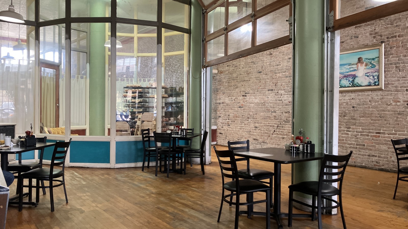 Brick dining room with tall windows and wood floors inside Bisbee Breakfast Club