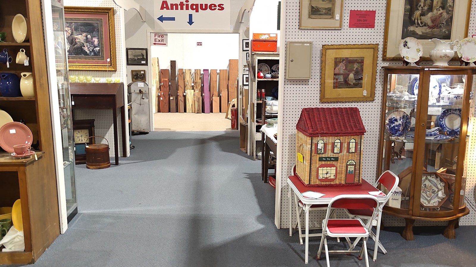 Aisle at Exit 76 Antique Mall with a More Antiques sign hanging above deeper vendor rows