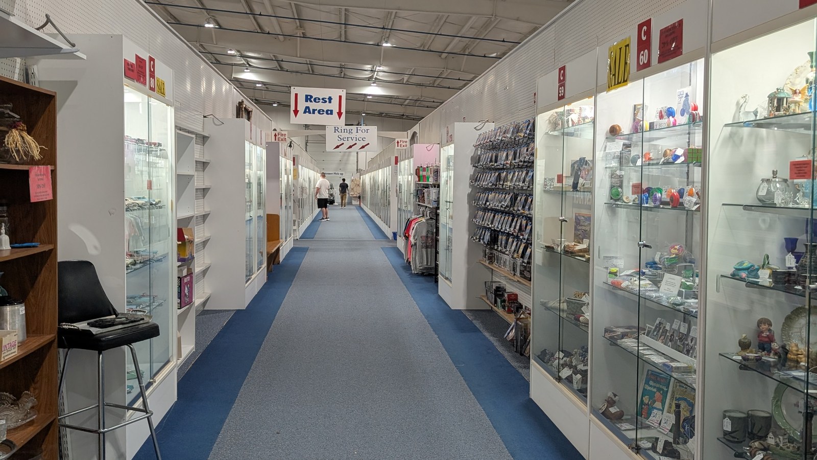 Long blue-carpet corridor lined with glass display cases and a rest area sign at Exit 76 Antique Mall