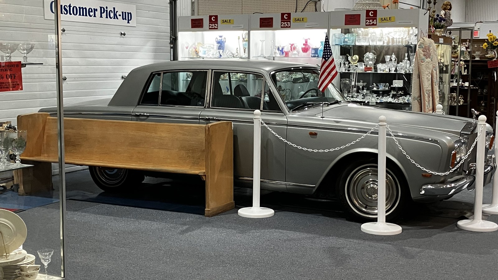 Silver classic car on display inside Exit 76 Antique Mall near glass cases and a customer pickup area