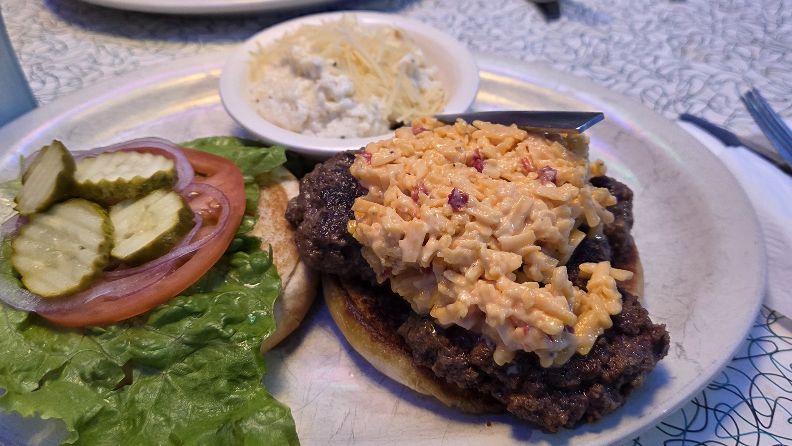 Loaded burger plate with pickles and a creamy topping at Hot Rods 50's Diner