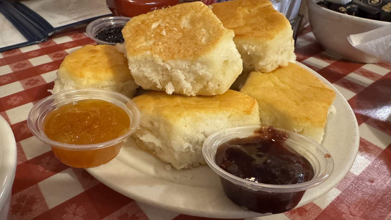 Plate of Loveless Cafe biscuits with peach and berry preserves on a checkered tablecloth