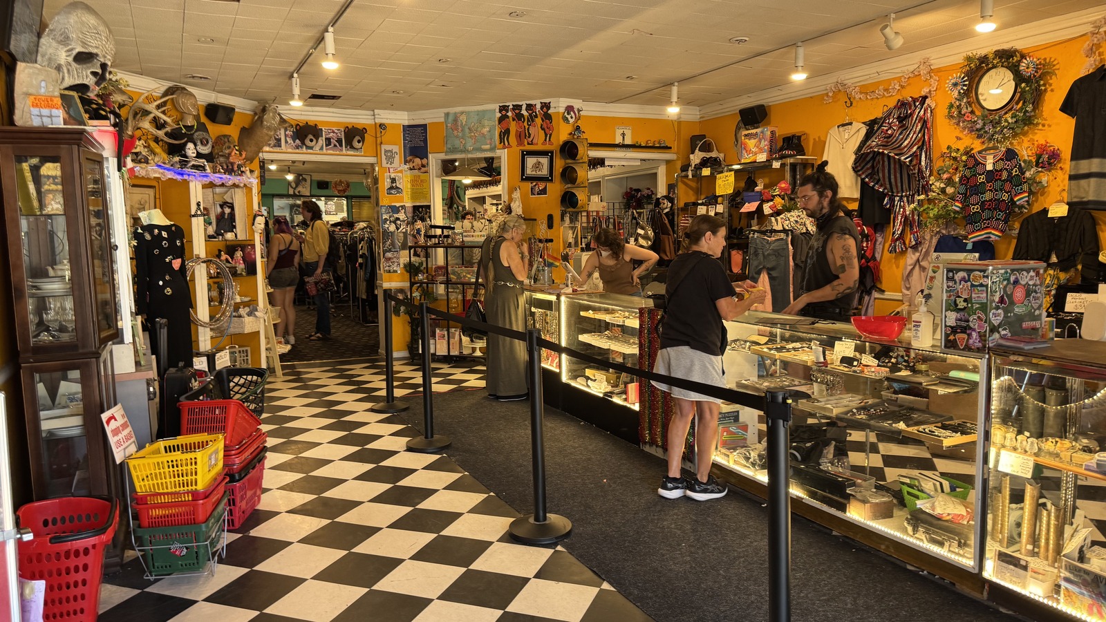 Checkerboard entry room with display cases and bright yellow walls at Philly AIDS Thrift in Philadelphia