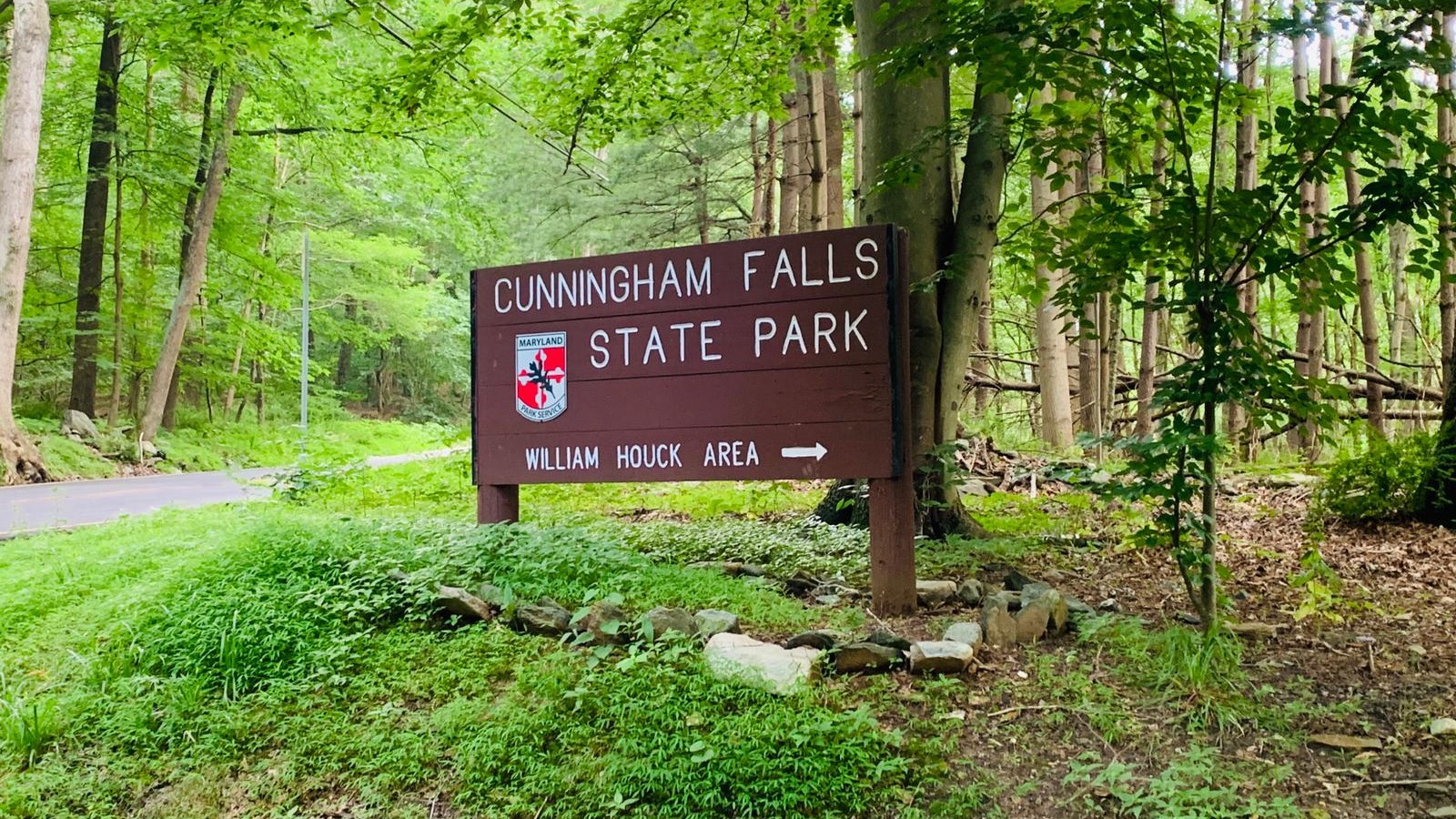 Cunningham Falls State Park sign beside the wooded William Houck Area road.