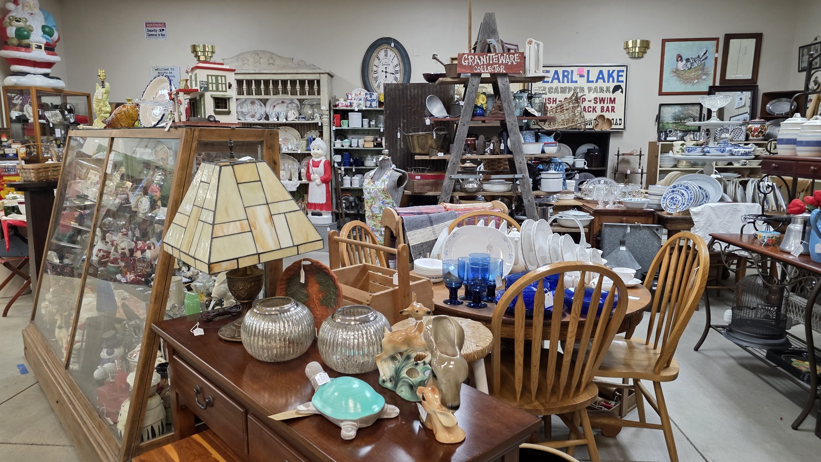 Dining table, blue glassware, display cabinet, and antique furniture inside Vintage Treasures Antique Mall in Fort Wayne