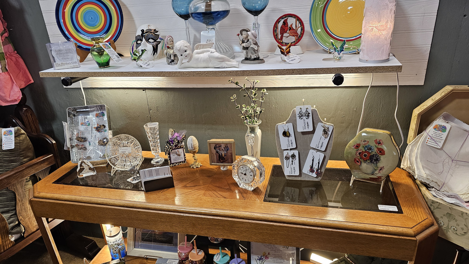 Glassware and tabletop antiques arranged on a wooden display inside America's Antique Mall in Highland