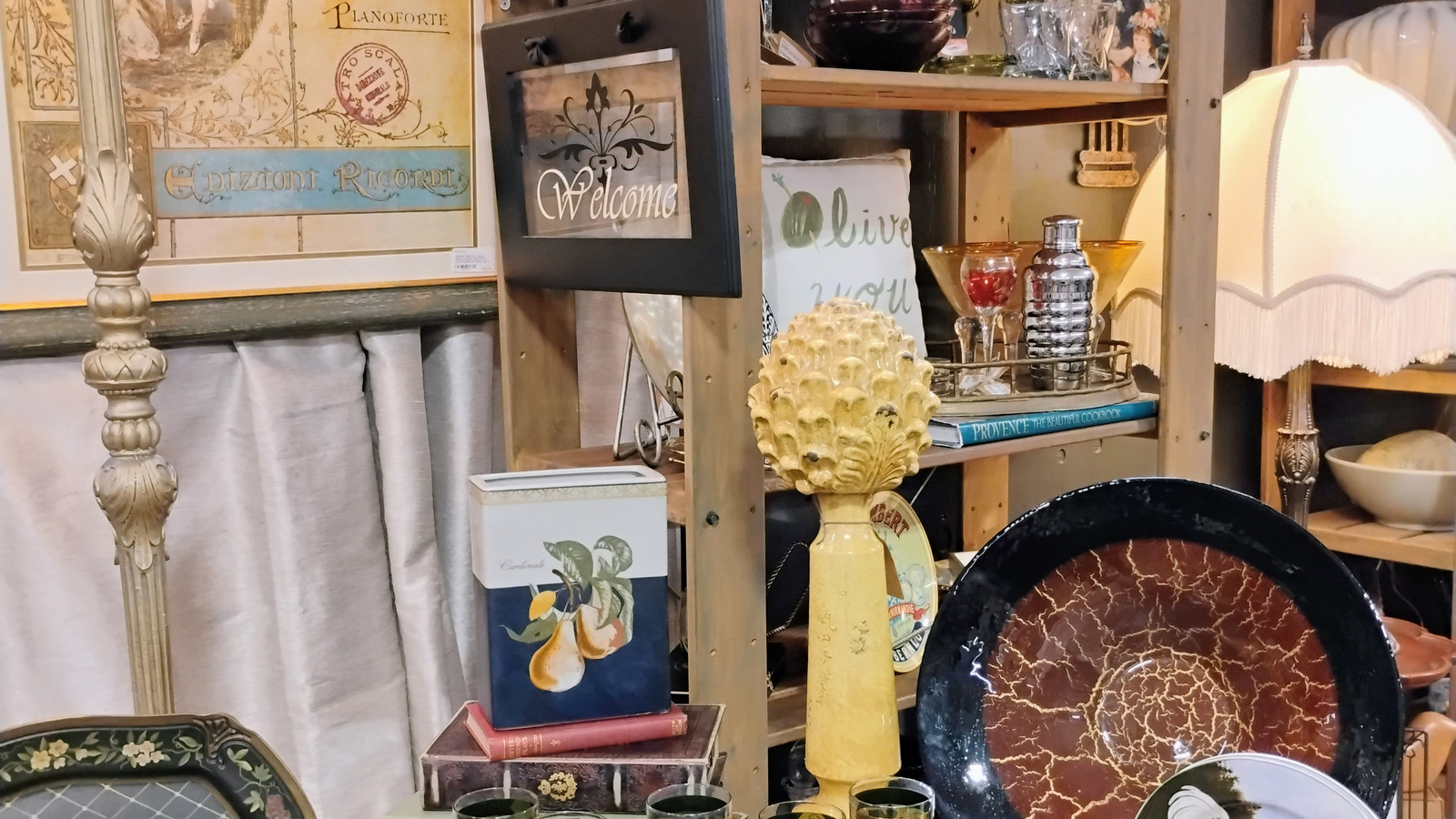 Decorative shelf with framed art, glassware, and vintage accents at America's Antique Mall in Highland