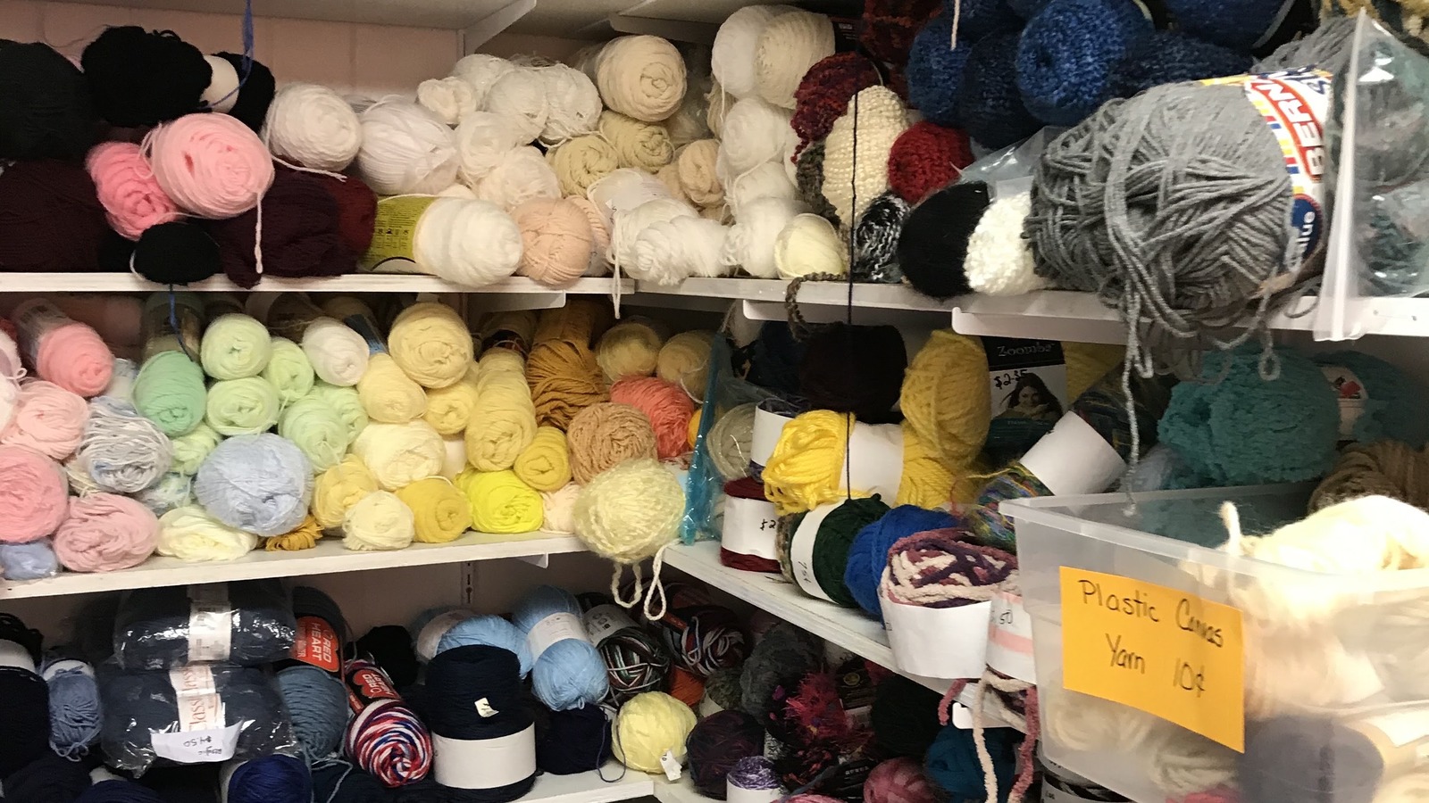 Shelves packed with yarn in pastel, neutral, and deep tones at Lancaster Creative Reuse.